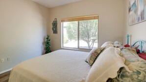 A bedroom with a large bed, a window with blinds, a ceiling fan, and a wall-mounted decoration. - Inviting Surprise Home With Covered Patio! (Surprise)