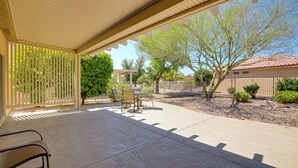 A covered patio with a table and chairs, a white fence, and a tree. - Inviting Surprise Home With Covered Patio! (Surprise)