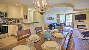 Una cocina moderna con armarios blancos, un microondas integrado y un comedor con una mesa de madera dispuesta para cuatro.