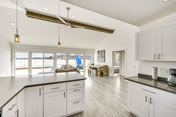 A spacious kitchen with white cabinets, a large island, and a view of a lake. - Lakefront Home w/ Boat Dock in Benton Harbor! (Benton Harbor)