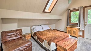 Ein Schlafzimmer mit Hochbett, einer Holzbank, einem kleinen Tisch, einem Fenster mit Vorhängen und einem Deckenventilator.