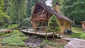 Eine Holzhütte mit Balkon, umgeben von einem Garten und einer Terrasse.