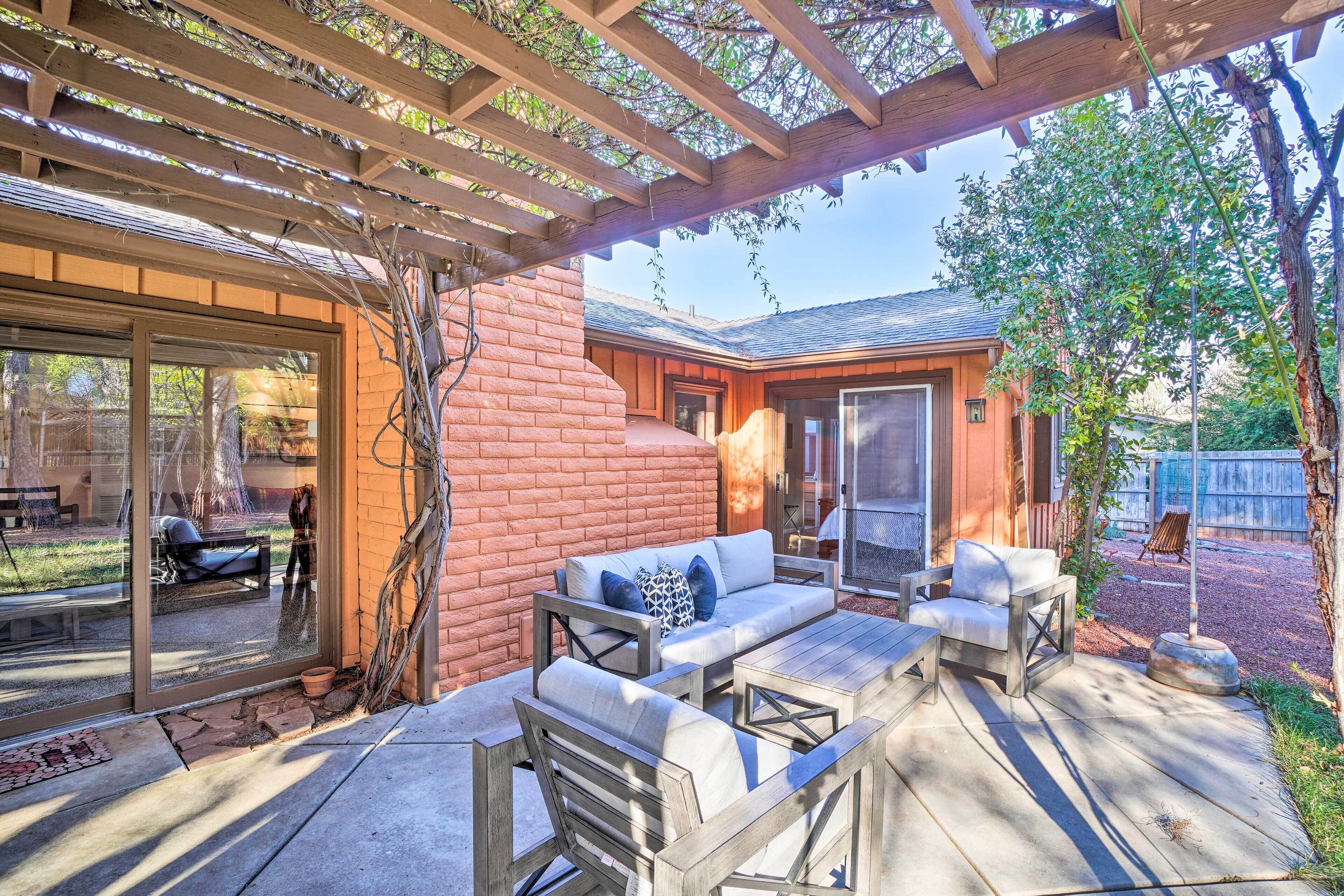 A covered patio with outdoor furniture, a brick wall, and a glass door leading to a patio area.