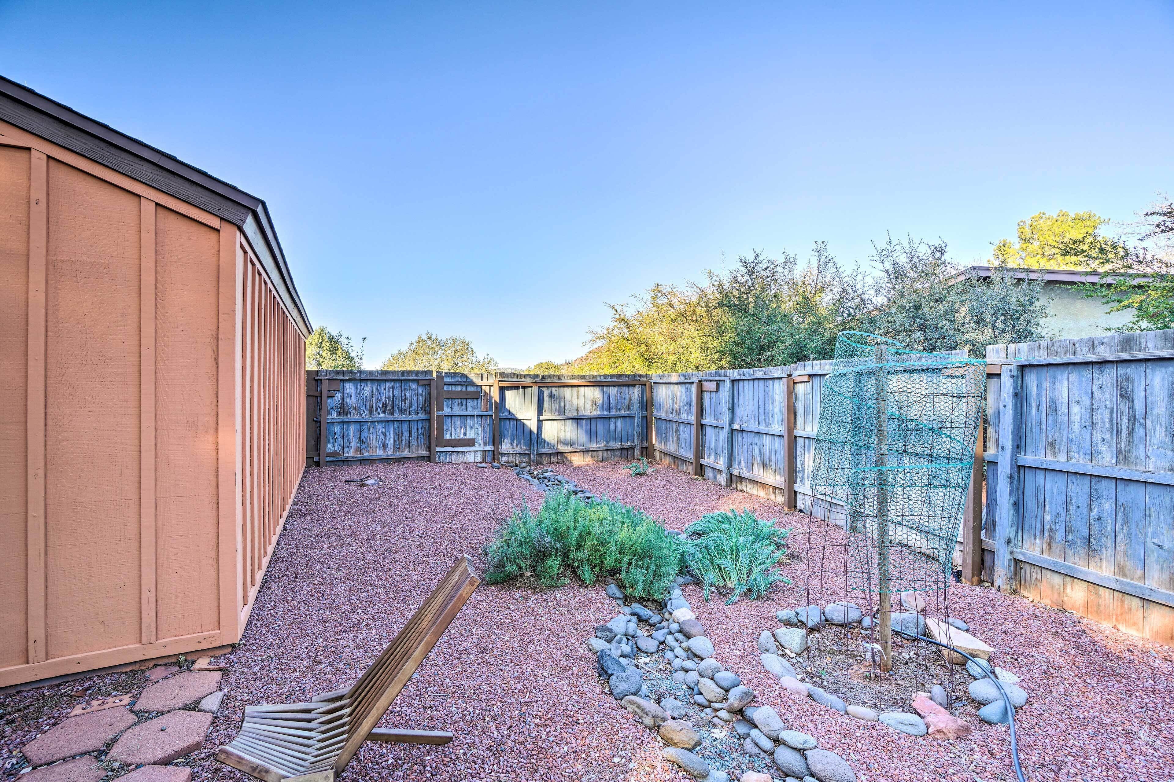 A backyard with a wooden shed, a wooden fence, and a garden area with rocks and plants.