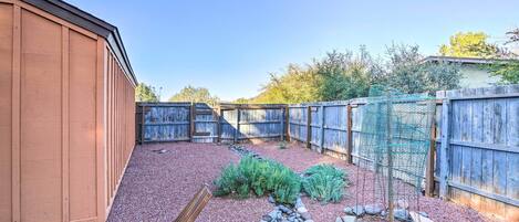 A backyard with a wooden shed, a wooden fence, and a garden area with rocks and plants.