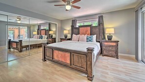 Ein Schlafzimmer mit einem großen Bett, einem Holzkopfende, Nachttischlampen, einem Deckenventilator und einem großen Spiegel.
