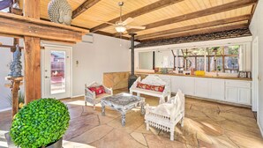 Ein großzügiger Patio-Bereich mit Steinböden, weißer Möbel und einem Deckenventilator.