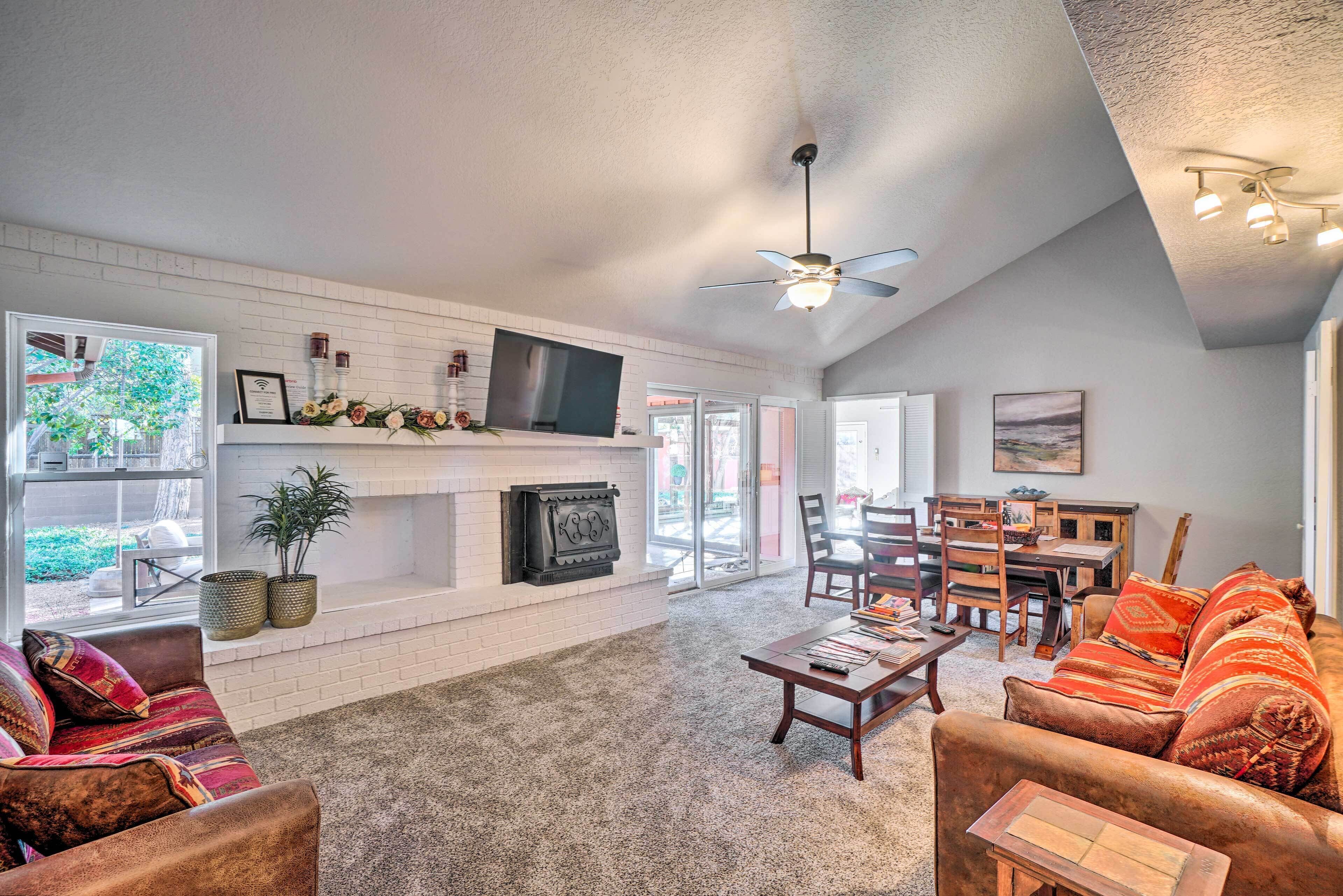A spacious living room with a fireplace, a television, and a dining area with chairs and a table.