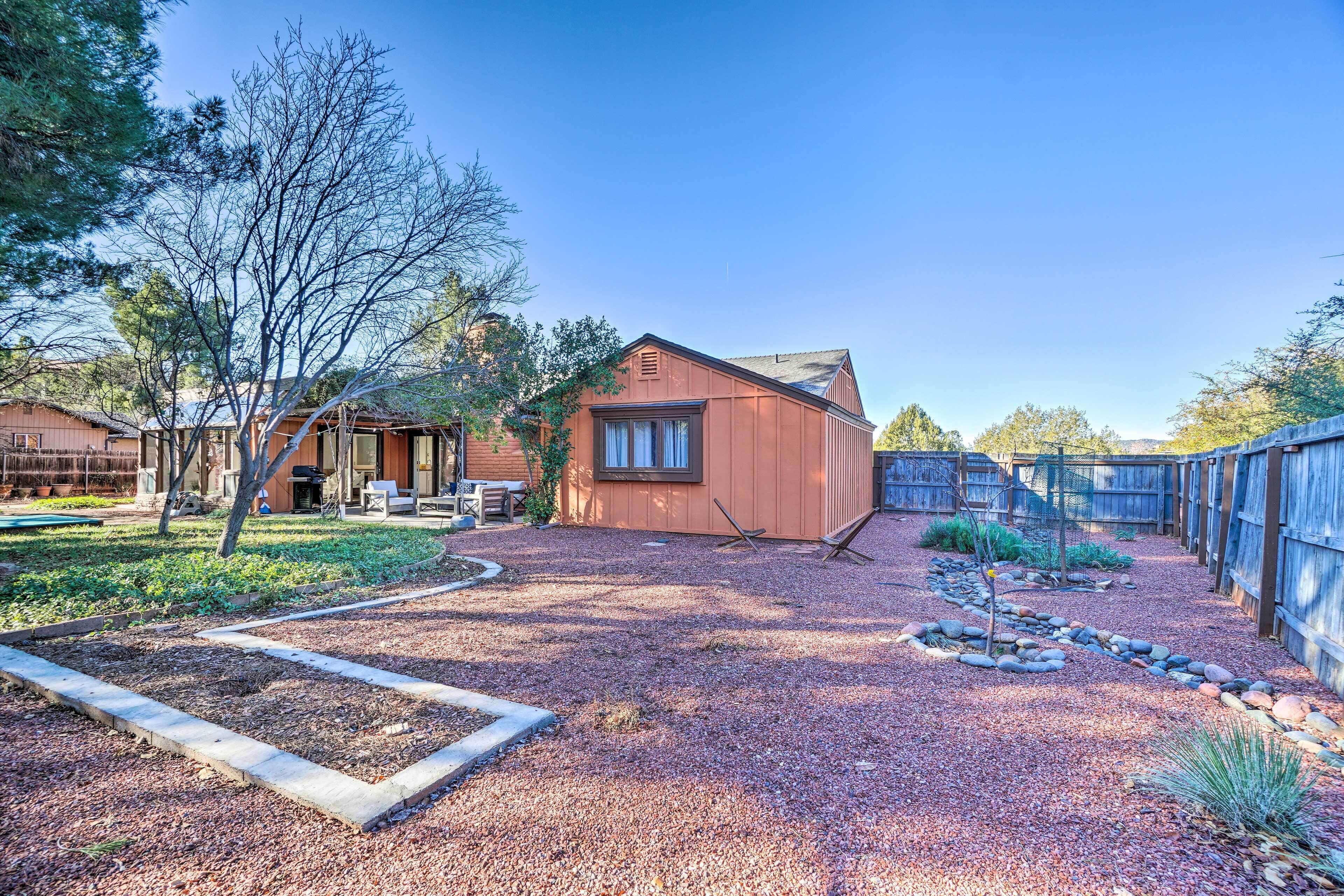 A residential property with a gravel driveway, a wooden fence, and a small garden area.