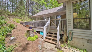 A cabin with a wooden deck, a staircase leading to a porch, and a surrounding forested area. - Scenic Sapphire Condo w/ Deck + Gas Grill! (Sapphire)