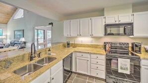 A modern kitchen with granite countertops, stainless steel appliances, and white cabinetry. - Scenic Sapphire Condo w/ Deck + Gas Grill! (Sapphire)