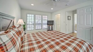 A bedroom with a plaid bedspread, a ceiling fan, a TV on a stand, and a window with blinds. - Scenic Sapphire Condo w/ Deck + Gas Grill! (Sapphire)