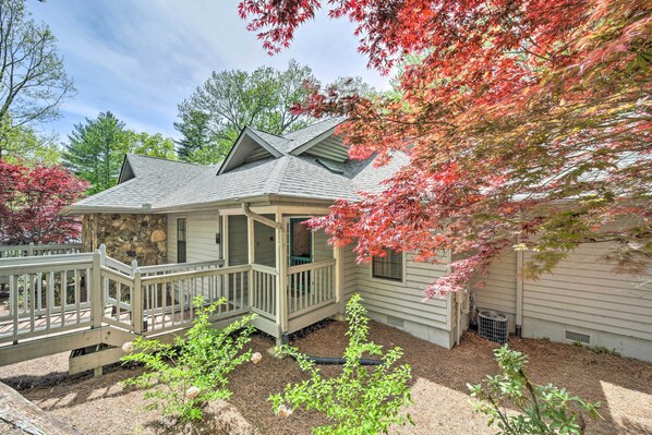 A house with a stone foundation, a covered porch, and a small garden area with mulch and plants. - Scenic Sapphire Condo w/ Deck + Gas Grill! (Sapphire)