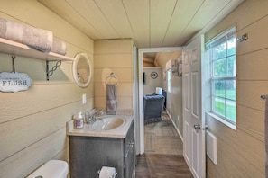 A bathroom with wooden paneling, a sink, a toilet, and a towel rack. - Quaint Montezuma Cabin Near Lake Ponderosa! (Montezuma)