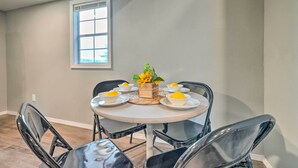 A dining area with a round table, black chairs, and a vase with yellow flowers. - Quaint Montezuma Cabin Near Lake Ponderosa! (Montezuma)