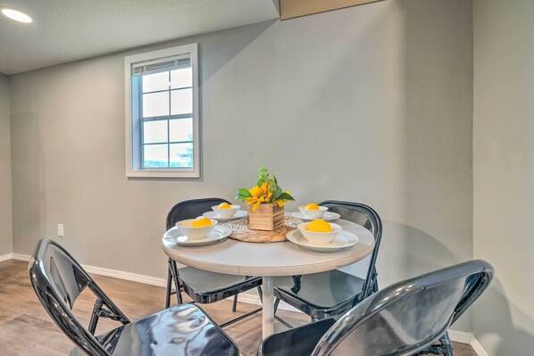 A dining area with a round table, black chairs, and a vase with yellow flowers. - Quaint Montezuma Cabin Near Lake Ponderosa! (Montezuma)