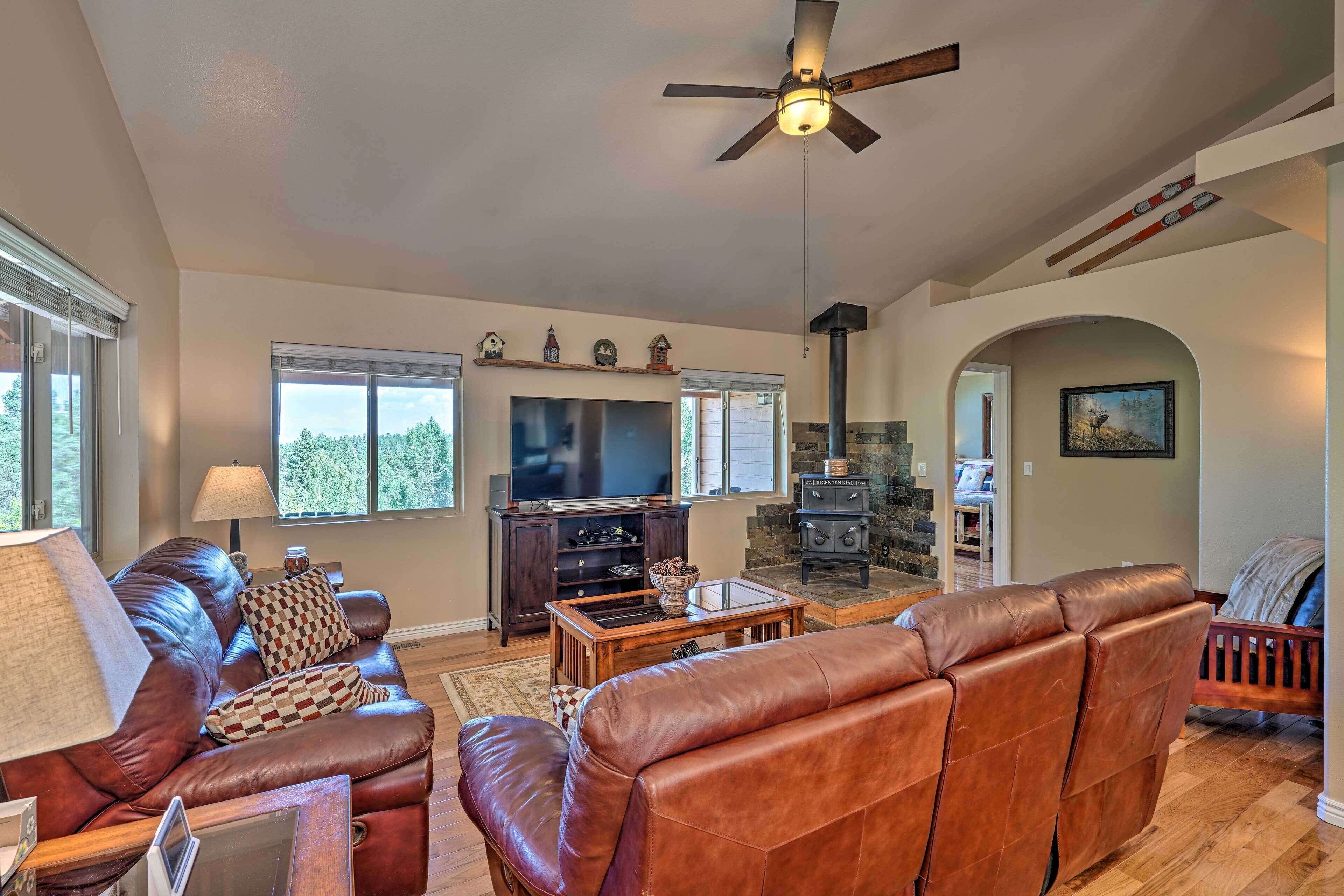 A spacious living room with a leather sofa, a television, and a fireplace.