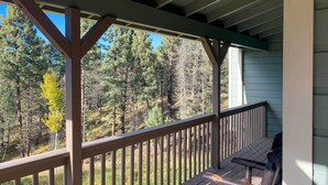 Une terrasse en bois avec un banc, donnant sur une zone boisée.