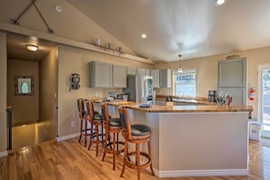 A kitchen with a central island, bar stools, and a view of the outside.