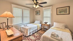 A hotel room with two beds, a ceiling fan, a bedside table with a lamp, a small table with a bowl, and a window with blinds. - Walkable Lake Elkhart Apt: Dine, Shop, Swim! (Elkhart Lake)