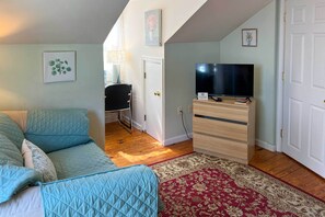 A room with a bed, a TV, a desk, and a chair.