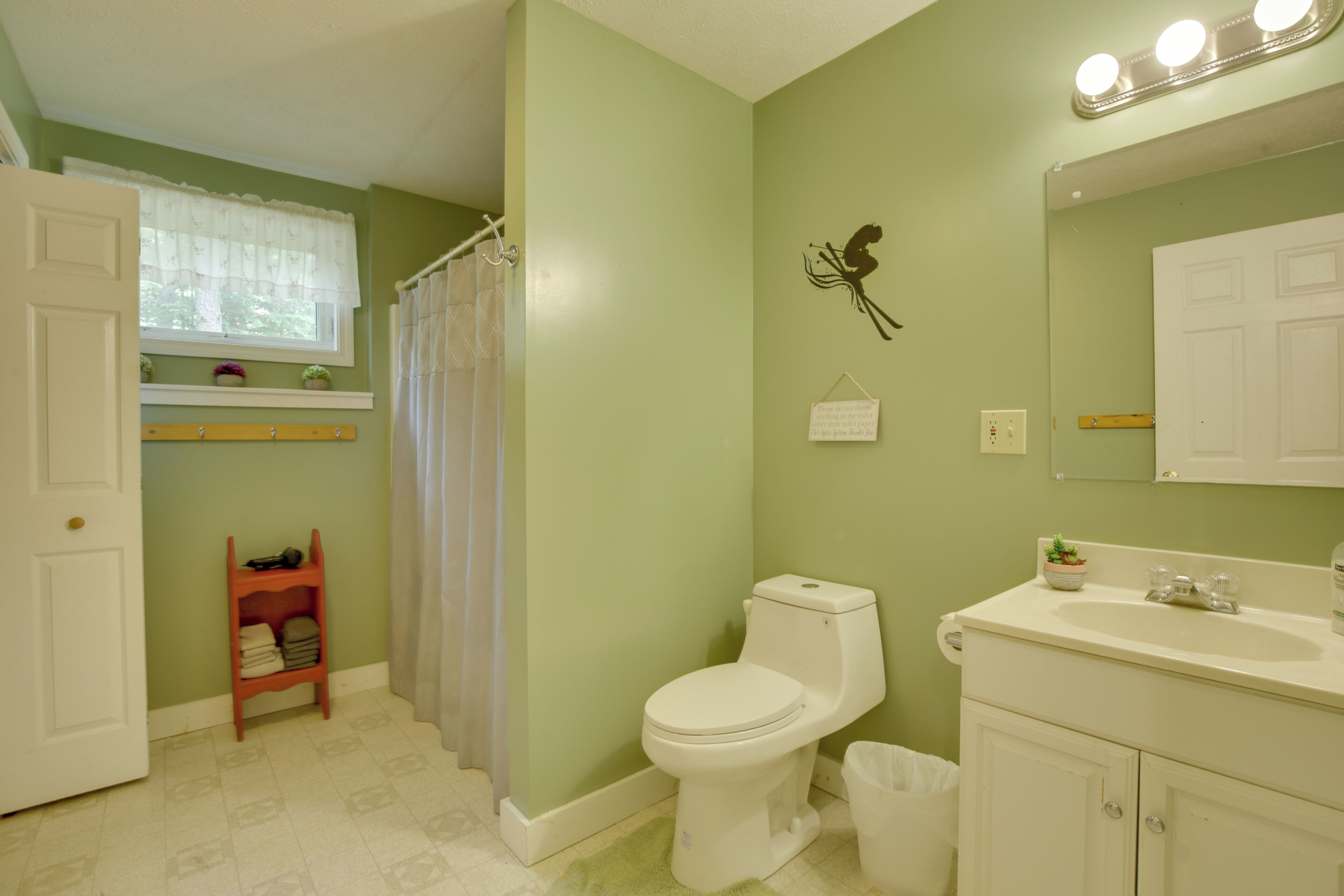 A bathroom with a toilet, sink, and shower curtain.