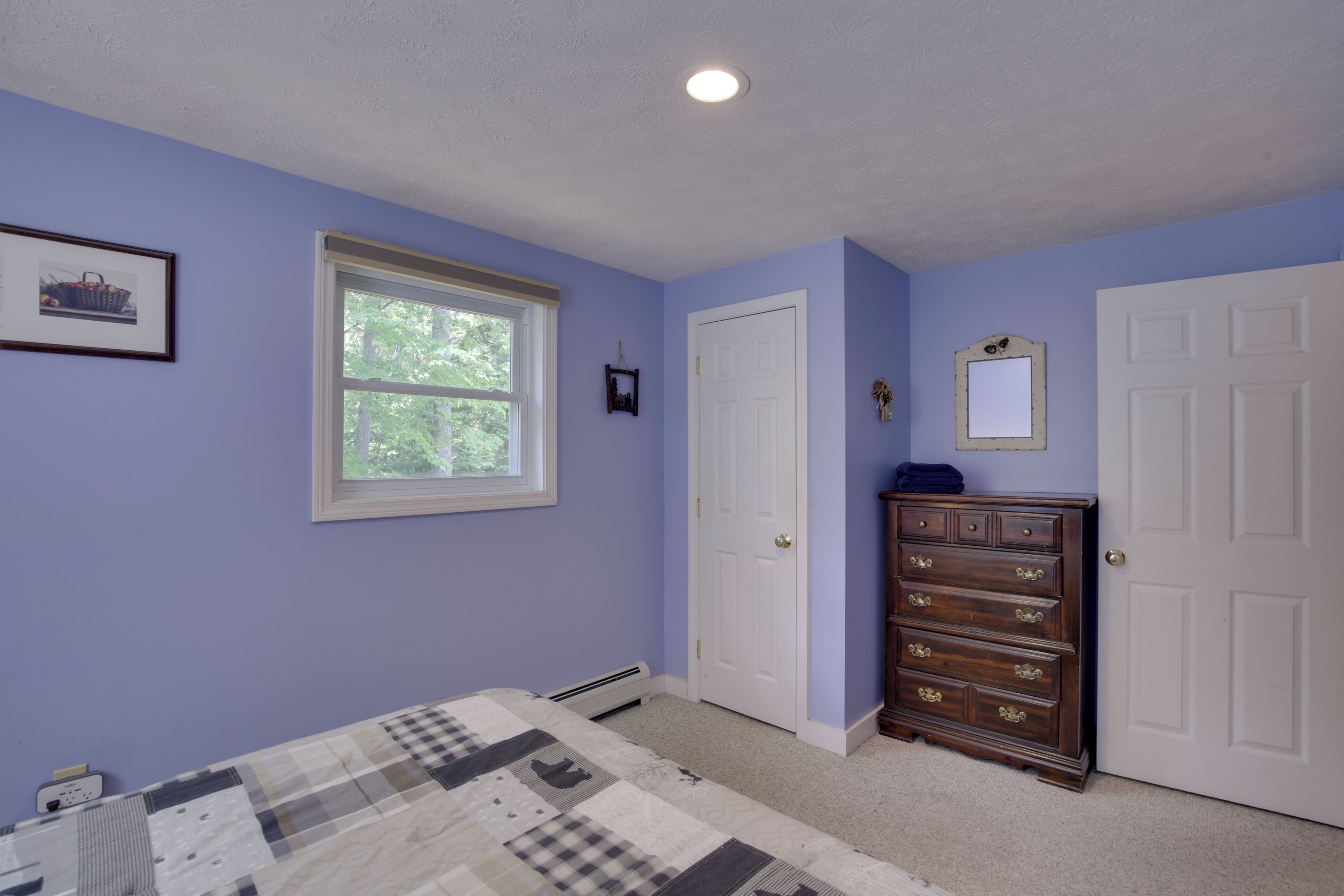 A bedroom with a bed, dresser, and a window.