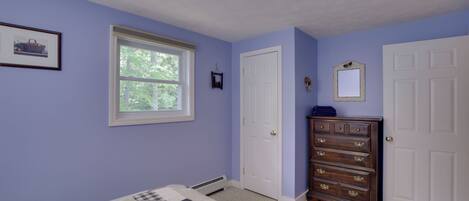 A bedroom with a bed, dresser, and a window.