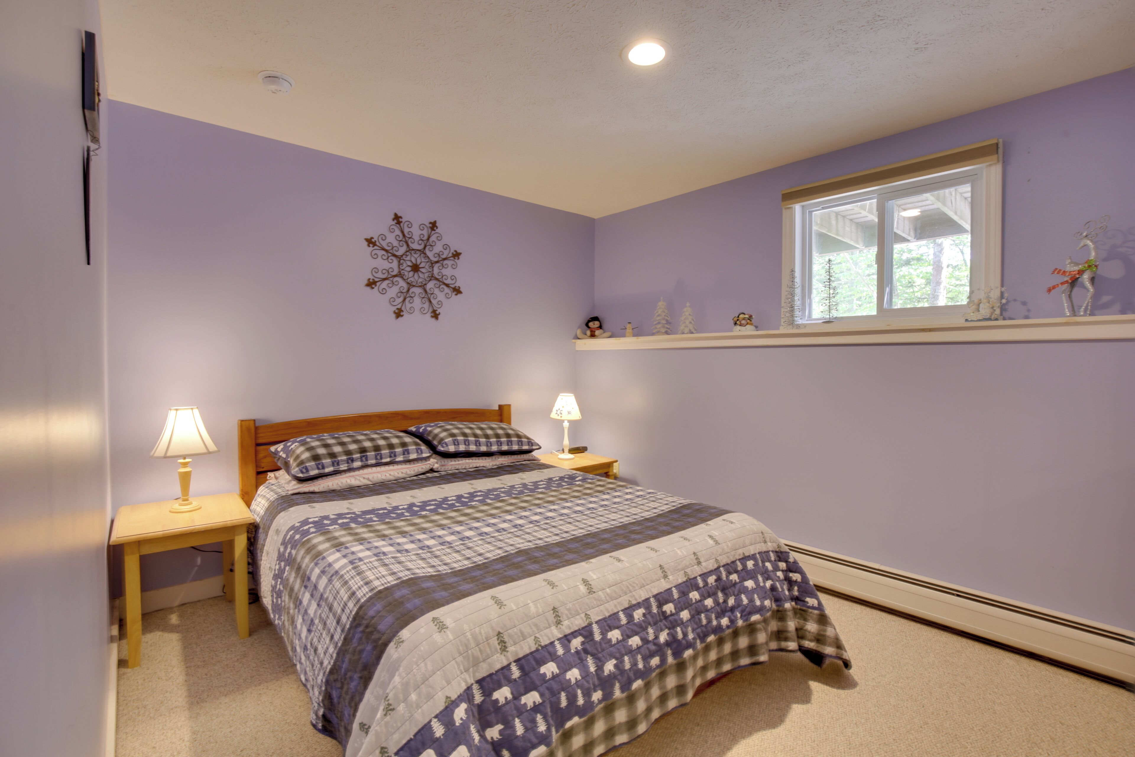 A bedroom with a bed, two bedside tables, a nightstand, a window, and a wall decoration.