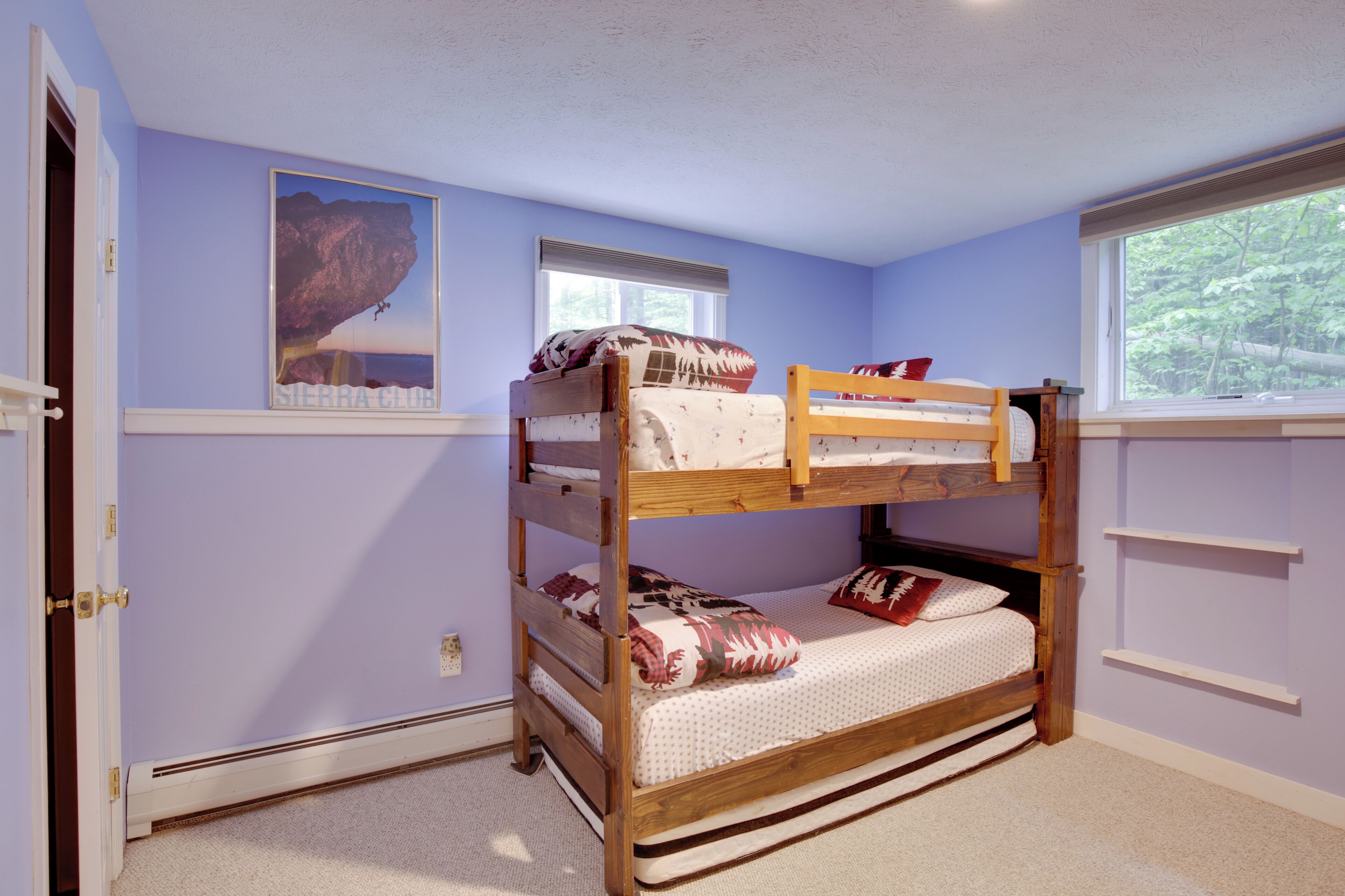 A bunk bed room with a window, a door, and a poster on the wall.