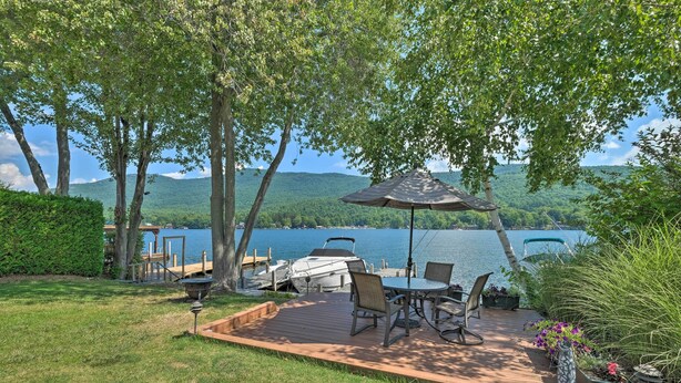 Une terrasse dotée de mobilier d’extérieur, d’un barbecue et offrant une vue sur un lac et des montagnes.
