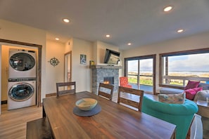A modern living room with a wooden dining table, a teal sofa, and a fireplace.