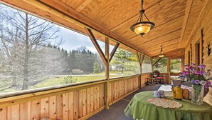 A wooden cabin with a covered porch, a table with a green tablecloth, and a view of the surrounding forest. - 'honey House Cabin' - A Quiet Countryside Retreat! (Nappanee)