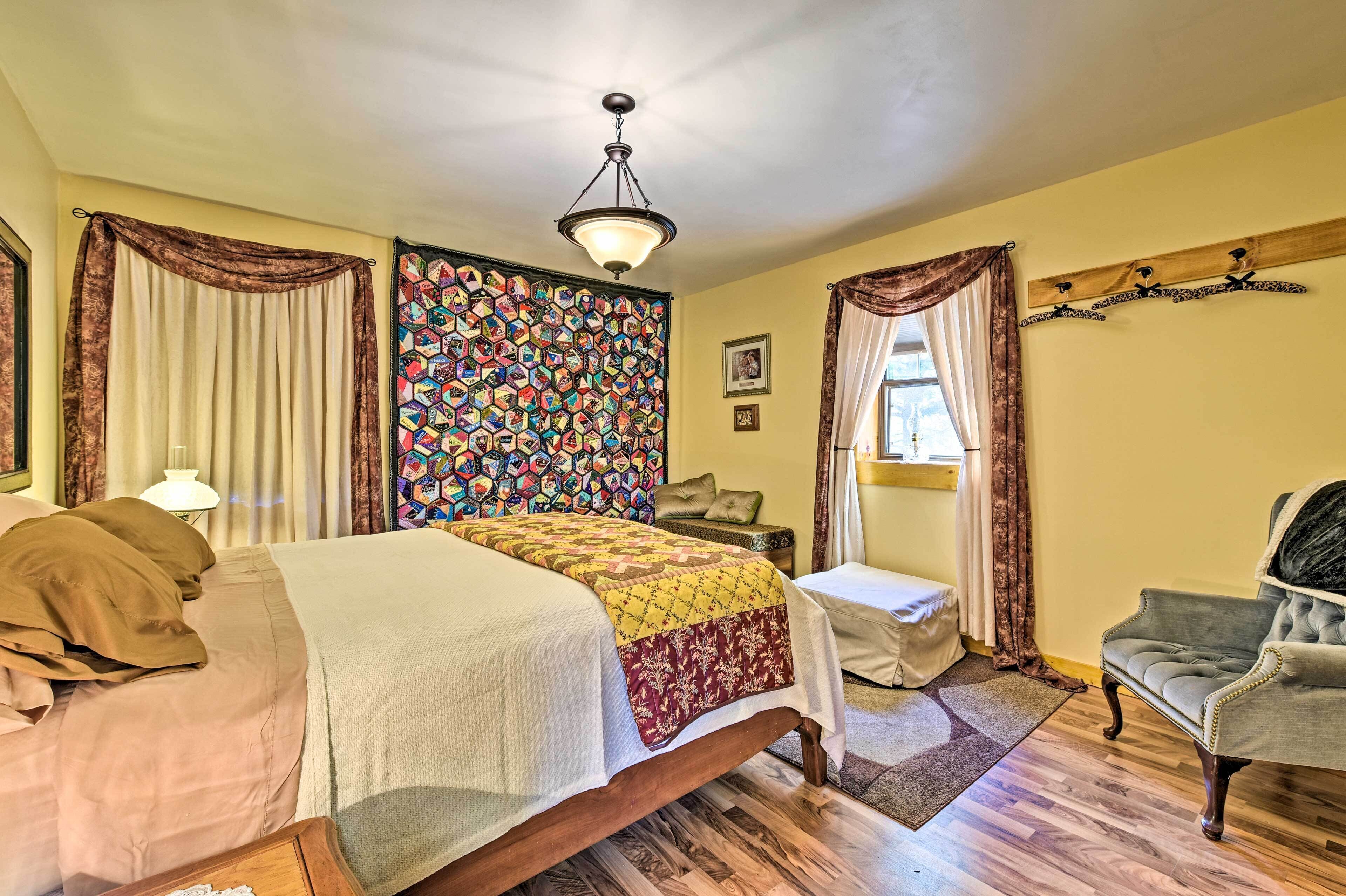 Quarto com cama, cadeira, mesa de cabeceira, parede com padrão colorido e luminária no teto.