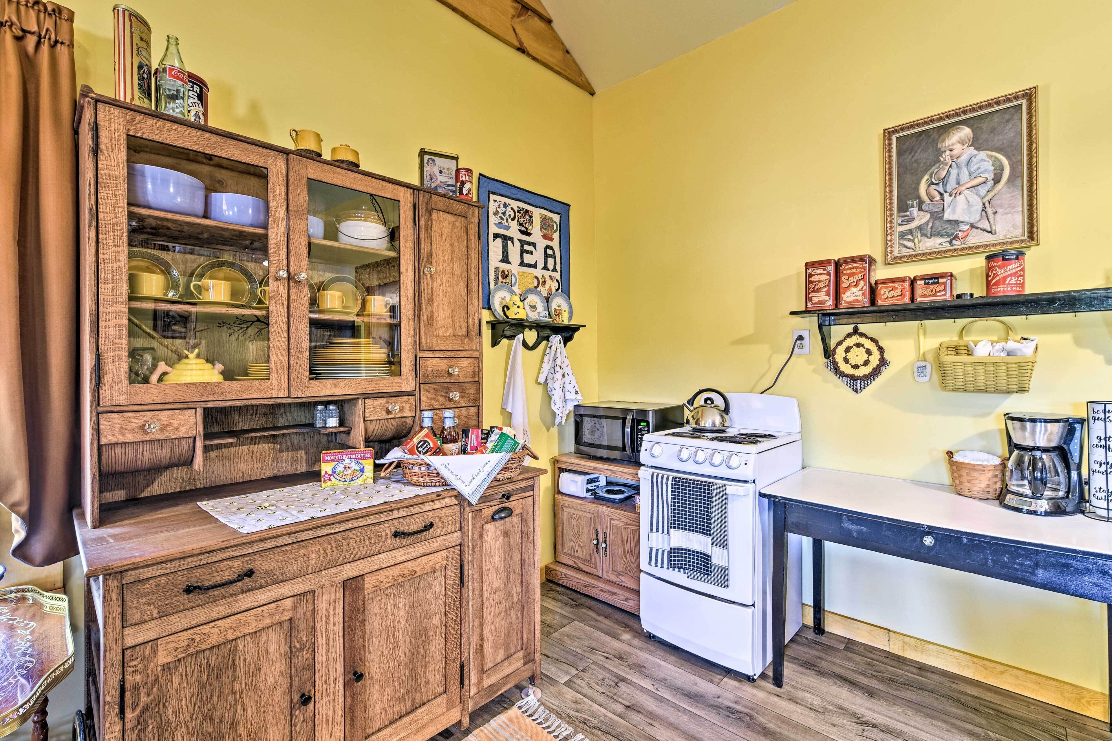 Una cocina con armarios de madera, microondas, horno y decoración temática de té.