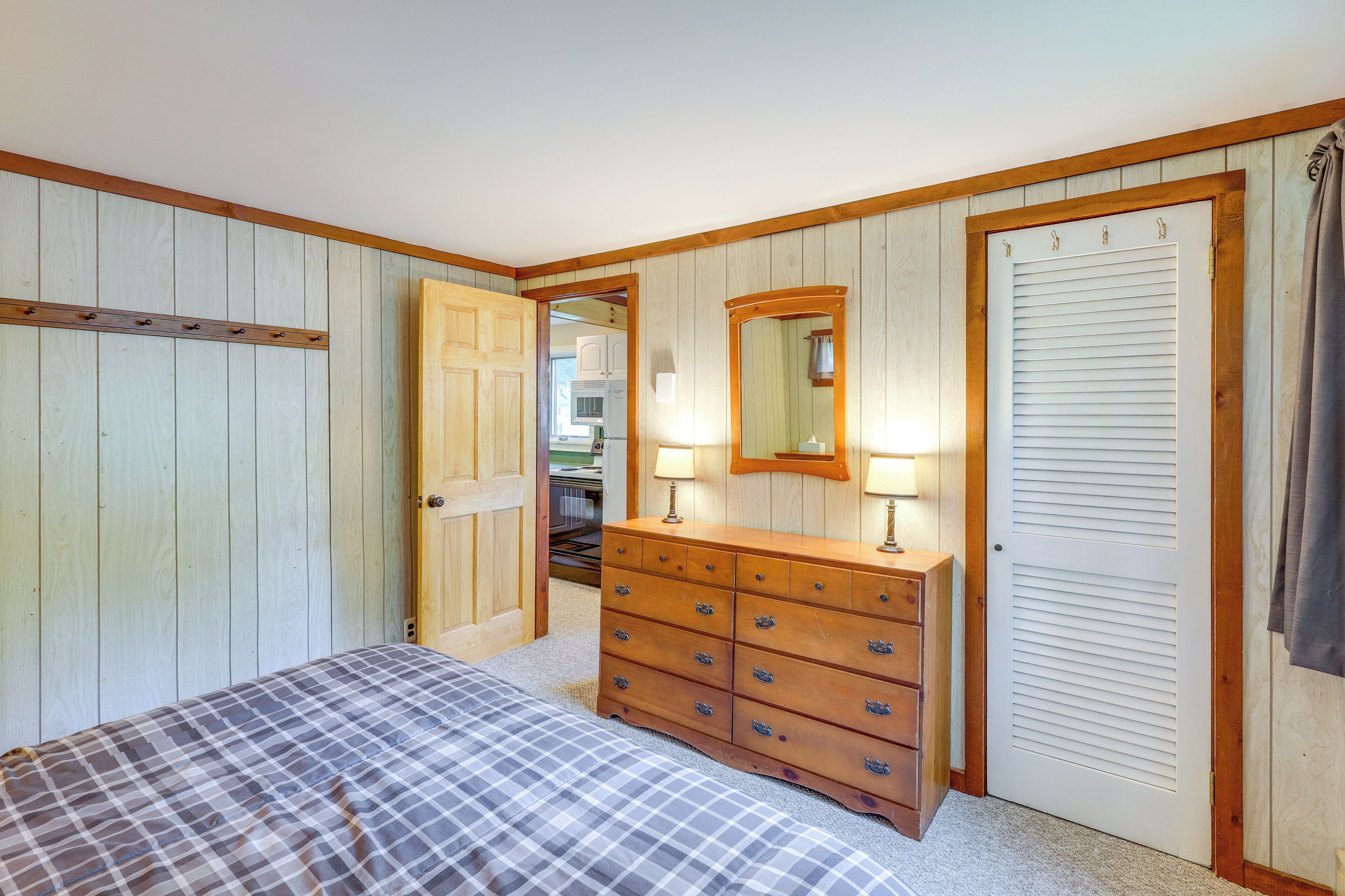 A bedroom with a bed, a dresser, a mirror, and a door.