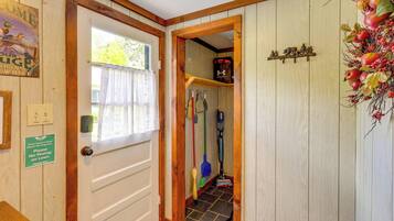 Una puerta de madera con un letrero que solicita no orinar en el césped, una ventana con cortina y un pasillo con utensilios de limpieza.