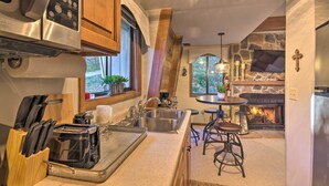 A modern kitchen with a stone fireplace, a built-in oven, and a large window.