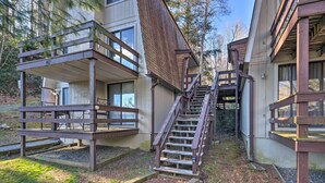 A building with a wooden staircase leading to a balcony, surrounded by trees.