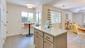 A kitchen with a granite countertop, wooden cabinets, and a window with a view of greenery.