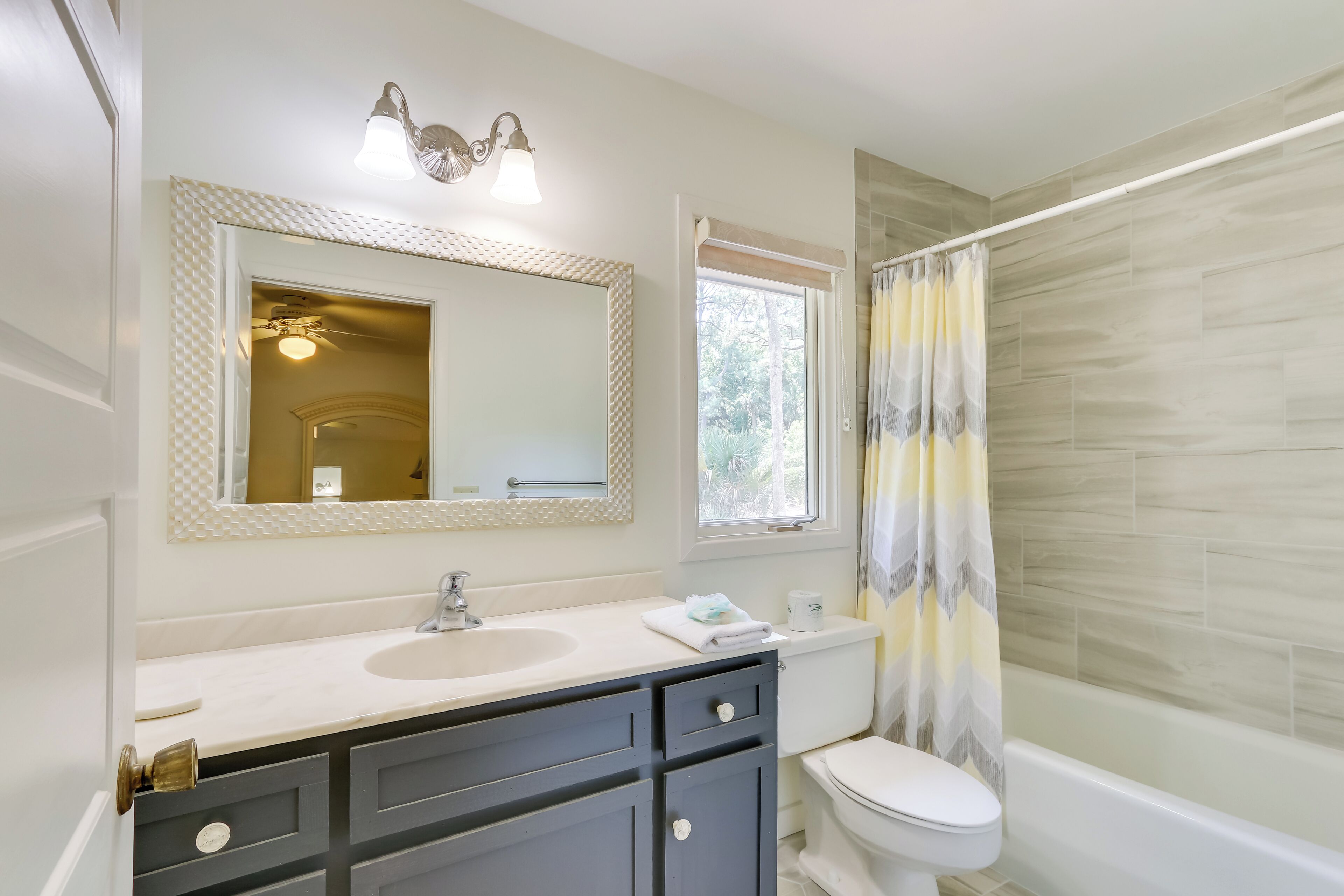 A bathroom with a white sink, dark cabinets, a toilet, and a shower with a patterned curtain.