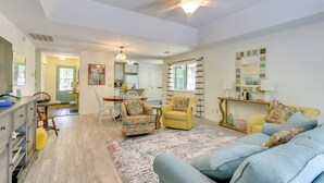 A spacious living room with a ceiling fan, a dining area with a table and chairs, and a kitchen in the background.