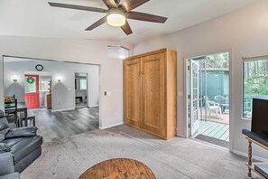 Ein geräumiges Wohnzimmer mit Deckenventilator, einer großen Holztür und einer Glastür, die zu einer Außenpatio führt.