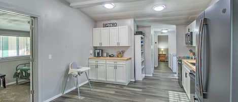 Eine moderne Küche mit weißen Schränken, einem Edelstahl-Kühlschrank und einem 'BISTRO'-Schild.