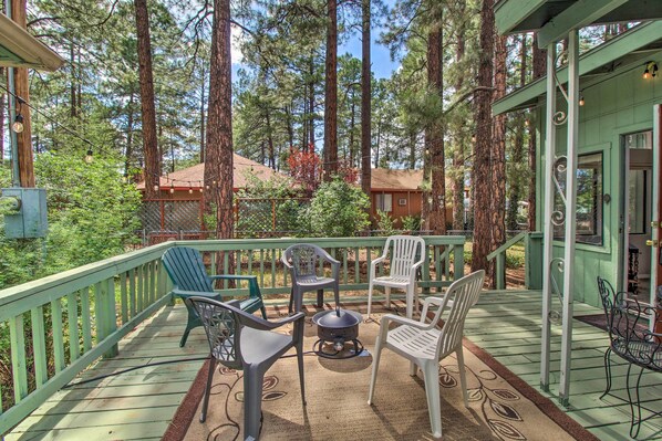 A wooden deck with outdoor furniture, surrounded by tall trees. - 2 Mi to Rainbow Lake: Woodsy Retreat w/ Deck! (Lakeside)