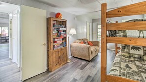 A room with a bunk bed, a wooden cabinet with toys, a lamp, and a sofa. - 2 Mi to Rainbow Lake: Woodsy Retreat w/ Deck! (Lakeside)