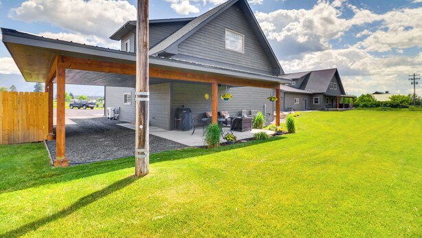 A two-story house with a covered patio, a garage, and a well-maintained lawn.