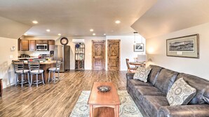 A spacious living area with a dark leather sofa, a wooden coffee table, and a kitchen area with modern appliances and a dining set.