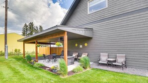 A covered patio with outdoor furniture, a fire pit, and a small garden area.