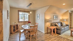 A dining area with a wooden table and chairs, a cabinet with wine glasses, and a window with natural light.